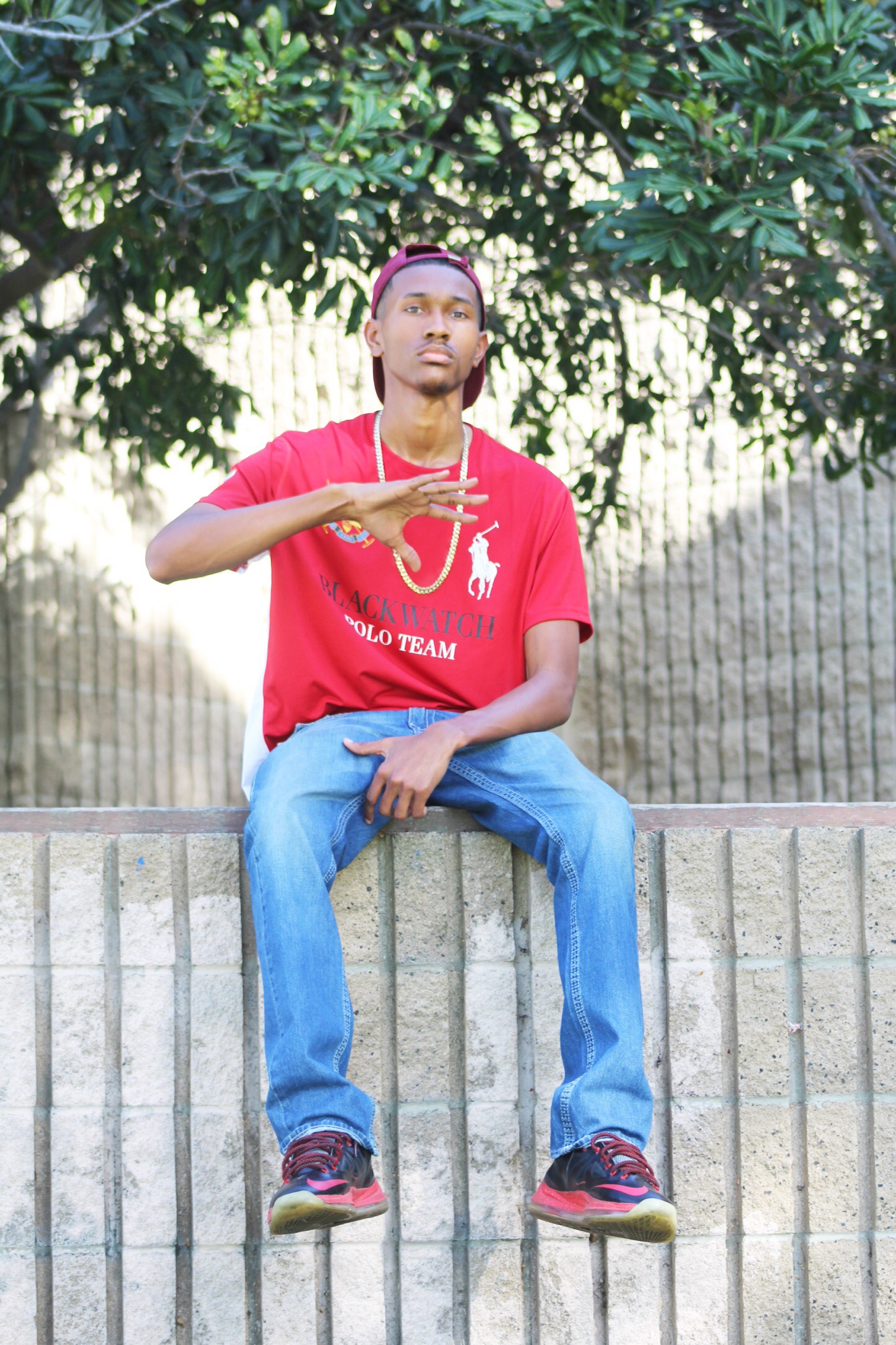 OTGFive seated outdoors in a red polo shirt